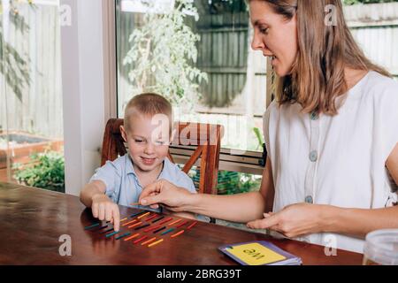 Mutter und ihr kleiner Sohn beim Zählen und Lesen zusammen und lächelnd. Homeschooling Konzept. Stockfoto