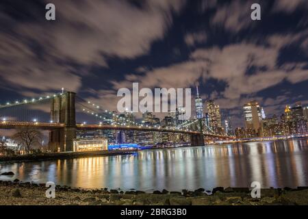 Eine lange Belichtung der Brooklyn Bridge, mit Blick auf Manhattan, aufgenommen vom Main Street Park in der Nacht, New York