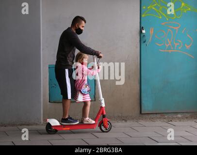 Krakau. Krakau. Polen. Vater, der mit Tochter E-Scooter fährt. Mädchen, das auf Smartphone-Bildschirm schaut. Stockfoto