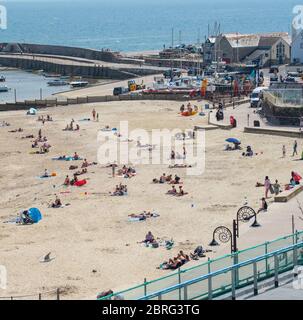 Lyme Regis, Dorset, Großbritannien. Mai 2020. UK Wetter: Einheimische und Familien genießen die heiße Nachmittagssonne im Badeort Lyme Regis. Obwohl die Parkplätze geschlossen blieben, war der Strand an diesem Nachmittag voller mit verantwortungsbewussten Strandbesuchern, die soziale Distanz aufrechterhalten, während sie die Sonne aufnässten. Kredit: Celia McMahon/Alamy Live News Stockfoto