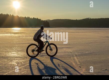Ein Mann, der im Winter ein Fatbike-Fahrrad auf dem Seereis fährt, Finnland Stockfoto