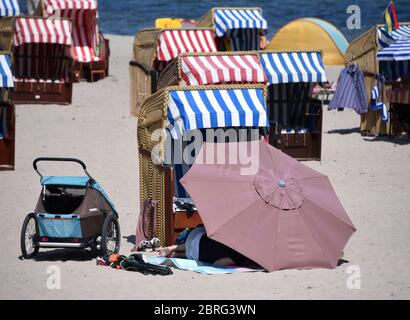 21. Mai 2020, Schleswig-Holstein, Lübeck-Travemünde: Ein Sonnenschirm wird vor einer Liege am Ostseestrand aufgestellt. Aufgrund der Entfernungsregeln während der Corona-Pandemie sind die Liegen auch ein paar Meter voneinander entfernt. Foto: Daniel Bockwoldt/dpa Stockfoto