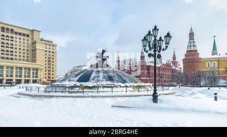 Manezhnaja Platz im Winter in Moskau, Russland. Panoramablick auf das Zentrum von Moskau bei Schneefall. Glaskuppel gekrönt von einer Statue des Heiligen Georg, Stockfoto