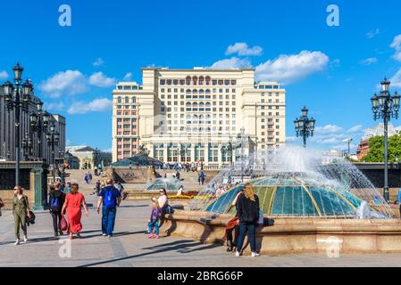 Moskau - 19. Mai 2019: Manezhnaja-Platz in Moskau, Russland. Wunderschöne Springbrunnen mit Blick auf das Four Seasons Hotel. Menschen gehen in der Moskauer Stadt Cen Stockfoto