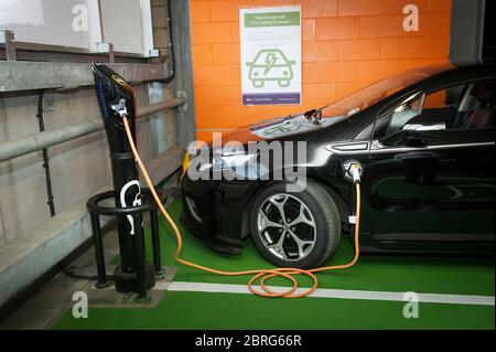Mit einer Ladestation für Elektroautos auf einem Parkplatz am Bahnhof, um ein Vauxhall Ampera Auto zu laden. Stockfoto