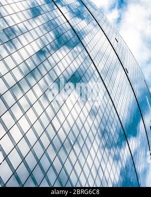 Abstrakter Architekturhintergrund. Der blaue Himmel spiegelt sich in einer Fassade des Bürohochhauses wider. Design aus Stahl und Glas. Konzept von Business und Finanzen. Stockfoto