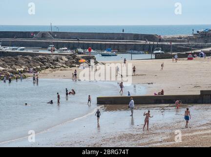 Lyme Regis, Dorset, Großbritannien. Mai 2020. UK Wetter: Einheimische und Familien genießen die heiße Nachmittagssonne im Badeort Lyme Regis. Obwohl die Parkplätze geschlossen blieben, war der Strand an diesem Nachmittag voller mit verantwortungsbewussten Strandbesuchern, die soziale Distanz aufrechterhalten, während sie die Sonne aufnässten. Kredit: Celia McMahon/Alamy Live News Stockfoto