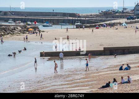 Lyme Regis, Dorset, Großbritannien. Mai 2020. UK Wetter: Einheimische und Familien genießen die heiße Nachmittagssonne im Badeort Lyme Regis. Obwohl die Parkplätze geschlossen blieben, war der Strand an diesem Nachmittag voller mit verantwortungsbewussten Strandbesuchern, die soziale Distanz aufrechterhalten, während sie die Sonne aufnässten. Kredit: Celia McMahon/Alamy Live News Stockfoto
