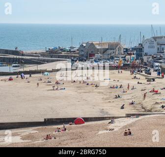 Lyme Regis, Dorset, Großbritannien. Mai 2020. UK Wetter: Einheimische und Familien genießen die heiße Nachmittagssonne im Badeort Lyme Regis. Obwohl die Parkplätze geschlossen blieben, war der Strand an diesem Nachmittag voller mit verantwortungsbewussten Strandbesuchern, die soziale Distanz aufrechterhalten, während sie die Sonne aufnässten. Kredit: Celia McMahon/Alamy Live News Stockfoto