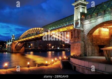 Puschkinski Brücke über Moskwa Fluss bei Nacht in Moskau, Russland. Schöne Aussicht auf die Moskauer Architektur mit Lichtern in der Dämmerung. Stockfoto