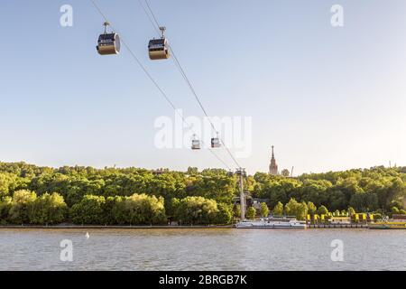 Panoramasicht auf die Seilbahn zwischen Sparrow Hills und Luzhniki-Stadion in Moskau, Russland. Seilbahnkabinen hängen am Himmel über dem Fluss Moskva in Mosco Stockfoto