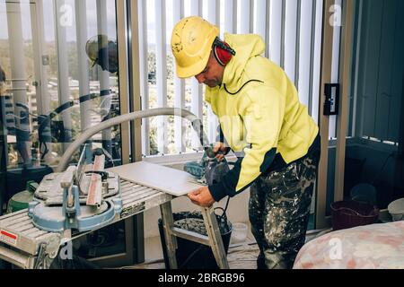 Professioneller Baumeister verschmiert Zementleim auf der Keramikfliesen mit einer Kelle. Konzept Renovierung Reparatur, Überholung, Auftragskachel. Stockfoto