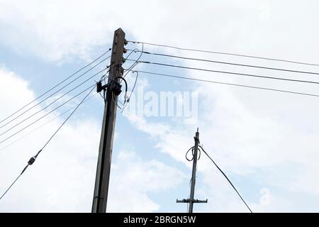 Strommast mit Stromleitungen, mit einem wolkigen blauen Himmel im Hintergrund. Stockfoto
