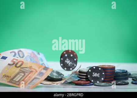 Poker spielt Chips auf einem Holztisch und grünen Hintergrund. Online-Glücksspiel. Sucht. Fallende Pokerchips. Fallende Euro-Banknoten. Geld verlieren. Stockfoto