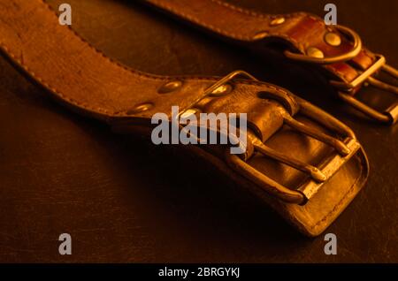 Fragment von zwei alten echten Lederhalsbändern auf einem dunklen Tisch. Zerbrochene, schäbige Leder- und Metallbeschläge. Echte Vintage Hundehalsbänder. Liebe zu den Tieren. Stockfoto