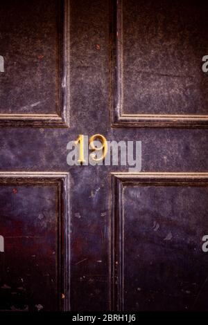 Haus Nummer 19 an einer dunklen Holztür in London Stockfoto