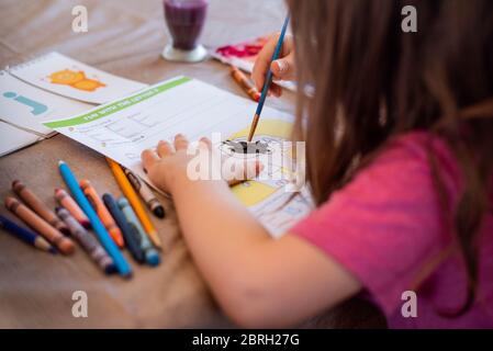 Ein 5-jähriges Mädchen malt mit einer Vielzahl von Aquarellfarben. Stockfoto