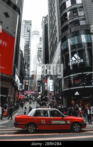 Rotes Taxi wartet auf einem Straßenrand einer luxuriösen Einkaufsstraße auf Hong Kong Island in China Stockfoto