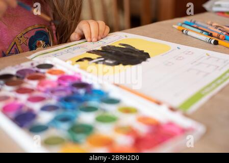 Ein 5-jähriges Mädchen malt mit einer Vielzahl von Aquarellfarben. Stockfoto