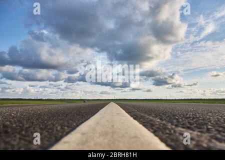 Leere Asphaltstraße auf einem Hintergrund von schönen bewölkten Himmel, Nahaufnahme. Stockfoto