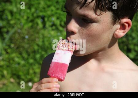 Kind genießt einen FAB Eis Lully an einem sonnigen Tag draußen in einem britischen Garten Stockfoto