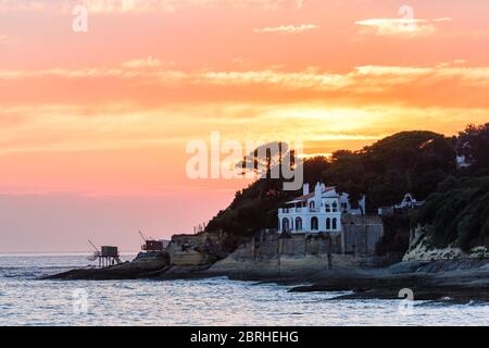 Saint-Palais-sur-Mer, Frankreich: Traditionelle Fischerhütten und eine luxuriöse Villa mit Meerblick, an der Küste nahe dem Stadtzentrum bei Sonnenuntergang gebaut. Stockfoto