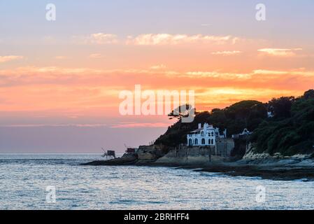 Saint-Palais-sur-Mer, Frankreich: Traditionelle Fischerhütten und eine luxuriöse Villa mit Meerblick, an der Küste nahe dem Stadtzentrum bei Sonnenuntergang gebaut. Stockfoto