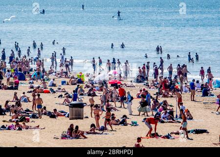 Strandbesucher entspannen und genießen die Sonne am Strand von Scheveningen am Himmelfahrtstag.warmes Wetter zog Menschenmassen an den Strand am Himmelfahrtstag trotz Empfehlungen, Abstand inmitten des Coronavirus-Ausbruchs zu halten. Stockfoto