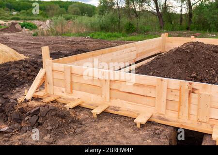 Holzschalung zur Erstellung von Streifenfundamenten für neue Hausbasis. Bau Haus von Anfang an Konzept Stockfoto