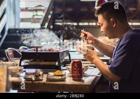 Xian, Provinz Shaanxi / China - 3. August 2015: Mann, der die lokale Xian Küche mit chinesischen Speisen in Xian, China, genießt Stockfoto