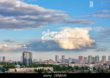 Die Sonnenstrahlen leuchten die gedachte Wolke bei Sonnenaufgang über der erwachenden Stadt hell auf. Leuchtendes Licht am blauen Morgenhimmel. Stockfoto