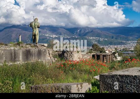 Pompeji Ruinen mit roten Mohnblumen im Frühling, Italien. Links - die Bronzeskulptur von Igor Mitoraj - Daedalus, die Pompeji geschenkt wurde. Panorama Stockfoto