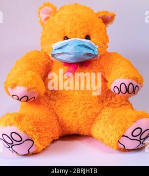 Medizinische Schutzmaske trägt Orange Teddybär Spielzeug Stockfoto