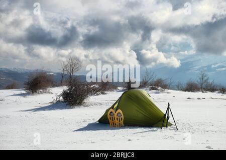 Wild Camp im Zelt auf dem Schnee von Nebrodi Park Naturdenkmal in Sizilien, auf Hintergrund verschwommen dramatischen Himmel Stockfoto