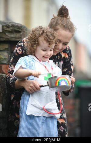 Swansea, Wales, Großbritannien. Mai 2020. Die zweijährige Lillian Joy aus Swansea kleidet sich als kleine Krankenschwester und trifft eine Regenbogenbemalte Pfanne, um ihre Unterstützung für Schlüsselarbeiter und den NHS mit ihrer Mutter Bethan zu zeigen, während Clap für unsere Betreuer von außerhalb ihres Hauses. Quelle : Robert Melen/Alamy Live News Stockfoto