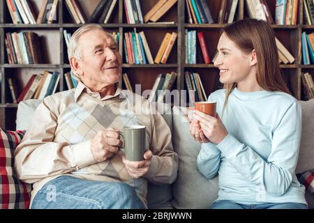Vater und Tochter zu Hause Bibliothek sitzen Tee trinken reden fröhlich Stockfoto