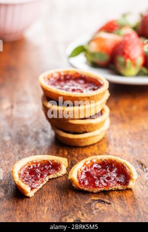 Süße Kekse mit Erdbeermarmelade auf Holztisch. Stockfoto