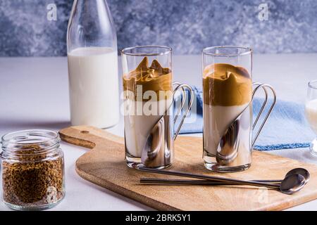 Dalgona Kaffee Espresso Latte mit einem kühlen flauschigen Schlagschaum in Gläsern auf grauem Hintergrund. Stockfoto