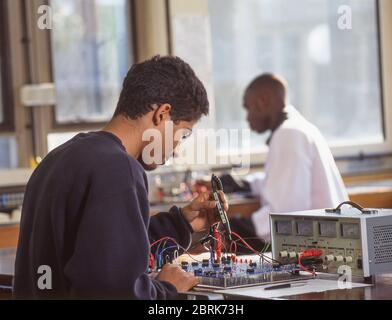 Schwarzer Student, der an Geräten in der Elektronikklasse arbeitet, Surrey, England, Großbritannien Stockfoto