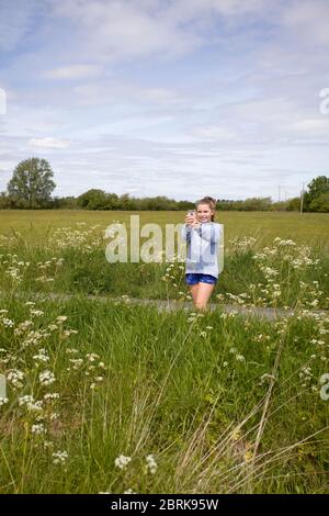 Junges Mädchen mit ihrem iPhone, um ein Foto auf dem Land, großbritannien Stockfoto