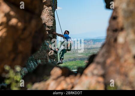 Kletterer klettert die Klippe mit Seilen und Ausrüstung, die Beschäftigung von Sportklettern Stockfoto