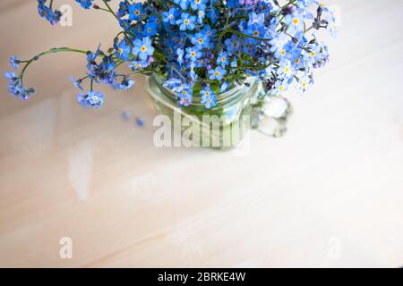 Bouquet von Vergissmeinnicht-Blumen in einer Glasschale auf einem unfokussierten Hintergrund Stockfoto