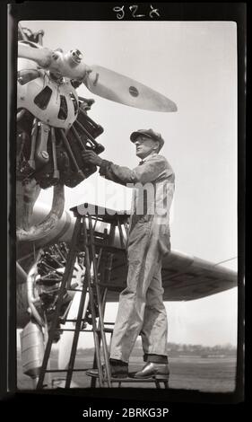 Wartungsarbeiter inspiziert ein Ford Tri-Motor-Flugzeug 1929. Diese Ansicht zeigt einen der drei Radialkolbenmotoren dieses historischen Transportflugzeugs. Bild von 4.25 x 2.5 Zoll negativ. Stockfoto