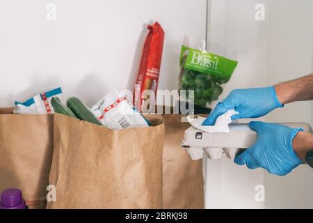 COVID-19: Ist es notwendig, Ihre Lebensmittel zu Hause geliefert zu reinigen. Mann in Quarantäne wischen Karton-Paket mit Desinfektionsmitteln Tücher nach dem Einkaufen oder Erhalt Online-Lieferung Taschen. Stockfoto