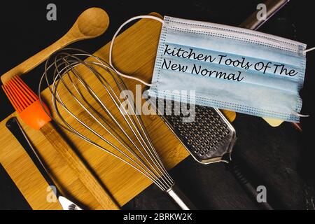Schriftzug der neuen Normalität auf Küchenutensilien und Werkzeugen. Gesichtsmaske in der modernen Küche. Stockfoto