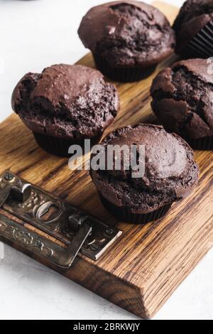 Leckere hausgemachte Schokoladenmuffins auf rustikalem Holzbrett Stockfoto