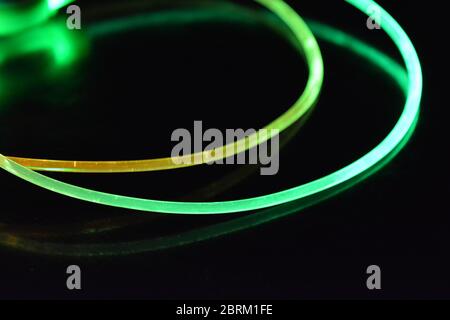 Draht mit grünem und rotem Licht, ein Lichtleiterkabel mit unterschiedlicher Lichtübertragung, Lichtspektrum und Lichteffekten in einem chaotischen Zustand. Stockfoto