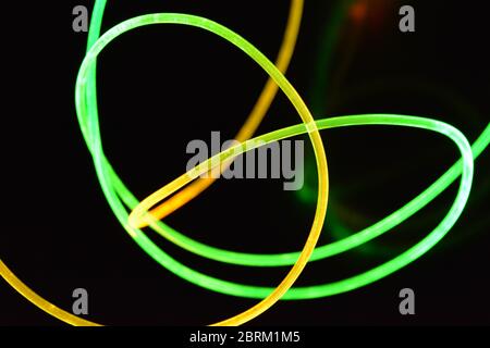 Draht mit grünem und rotem Licht, ein Lichtleiterkabel mit unterschiedlicher Lichtübertragung, Lichtspektrum und Lichteffekten in einem chaotischen Zustand. Stockfoto