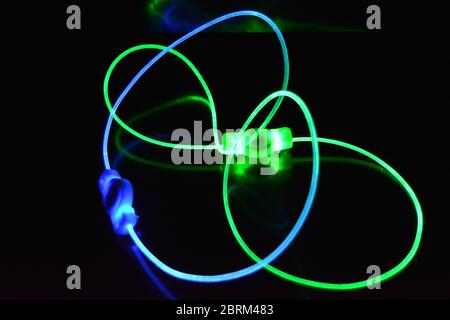 Grüner und blauer Lichtleiter, ein Lichtleiterkabel mit unterschiedlicher Lichtübertragung, Lichtspektrum und Lichteffekten, das sich in einem chaotischen Zustand befindet. Stockfoto