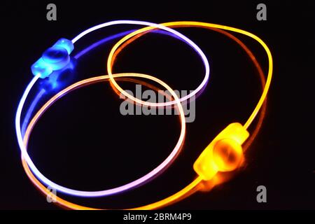Gelbes und blaues Lichtkabel, ein Lichtleiterkabel mit unterschiedlicher Lichtdurchlässigkeit, unterschiedlichem Lichtspektrum und Lichteffekten, das sich in einem chaotischen Zustand befindet. Stockfoto